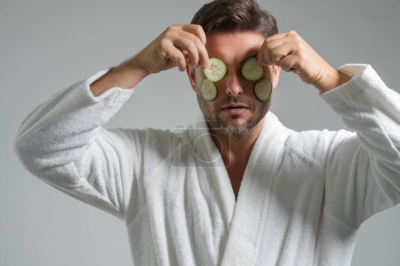 Clean face, face care, facials concept. Middle aged man with cucumber mask isolated on studio background. Cucumber for cosmetics skin mask. Facial mask with cucumber. Spa, dermatology