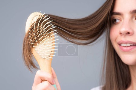 Photo for Close up young woman hairdresser with comb brushing hair. Brunette woman combing hair - Royalty Free Image