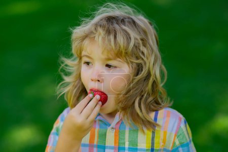 Photo for Summer kid face. Strawberries for kids. Child eat strawberry on summer green grass background - Royalty Free Image
