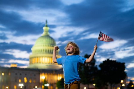 Foto de Fiesta patriótica americana. Niño americano, niño lindo con bandera americana cerca del edificio del Capitolio en Washington DC. Estados Unidos celebra el 4 de julio. El chico sostiene la bandera americana. Día de la Independencia - Imagen libre de derechos