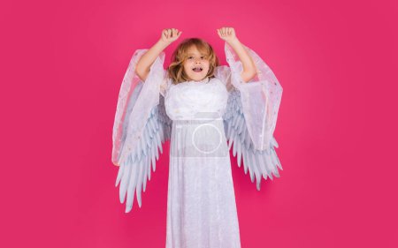 Téléchargez les photos : Saint Valentin. Blonde mignon enfant avec des ailes d'ange sur un fond rouge rose studio. Enfant ange heureux - en image libre de droit
