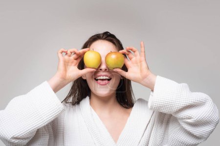 Foto de Retrato de una niña sonriente sosteniendo una manzana cerca de la cara, aislada en el fondo del estudio - Imagen libre de derechos