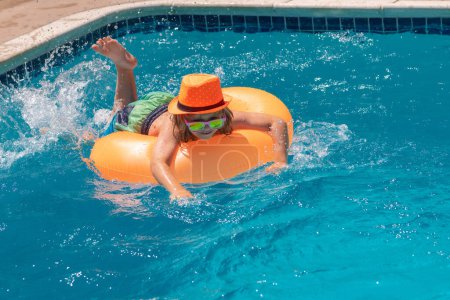 Téléchargez les photos : Les enfants drôles visage d'été. Enfant garçon dans la piscine avec anneau gonflable. Les enfants nagent dans la piscine d'eau pendant les vacances d'été. Nager pour enfant sur flotteur. Plage mer et eau plaisir - en image libre de droit