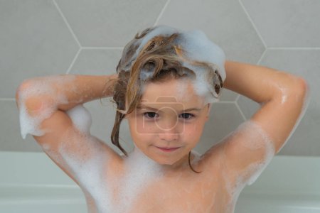 Foto de Niño lavando el cabello. Champú para niños. Feliz chico divertido bañado en el baño. Niño en la ducha. Los niños se enfrentan en el baño con espuma. Retrato de bebé bañándose en un baño lleno de espuma - Imagen libre de derechos