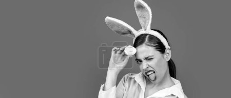 Téléchargez les photos : Bannière de Pâques avec lapin femme. Une jeune femme aux oreilles de lapin. Portrait d'une femme heureuse aux oreilles de lapin. Chasse aux œufs. Lèvres et Pâques, Empreinte baiser rouge à lèvres sur l'oeuf de Pâques - en image libre de droit