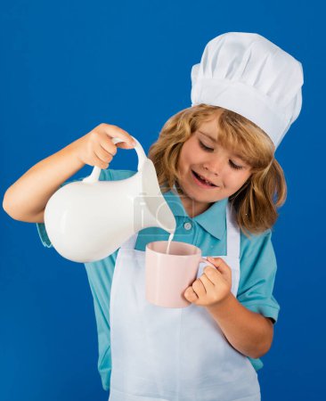 Téléchargez les photos : Du lait pour les enfants. Enfant chef isolé sur bleu. Drôle petit chef cuisinier enfant portant casquette de cuisinier uniforme et tablier cuisiné dans la cuisine - en image libre de droit