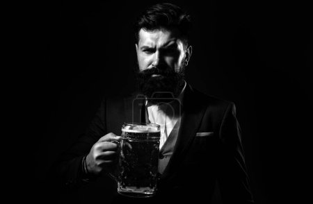 Portrait of serious bearded man drinking beer. Happy brewer holding glass with beer