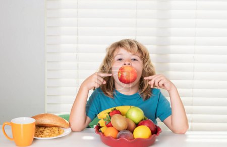 Photo for Fun child eating apple. Funny blonde little boy having breakfast. Milk, vegetables and fruits healthy food nutrition for children - Royalty Free Image