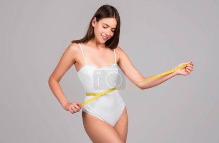 Attractive caucasian woman measuring her waist isolated background. Body care