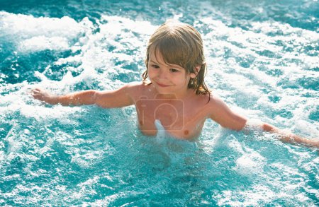 Happy kid playing in outdoor swimming pool on hot summer day. Kids learn to swim. Child in water. Children play in tropical resort. Family beach vacation