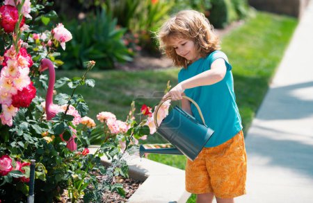 Foto de Lindo niño regando plantas en el jardín en verano día soleado - Imagen libre de derechos