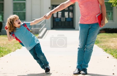 Téléchargez les photos : Père et fils excité marchant à travers le parc scolaire - en image libre de droit