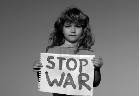 Téléchargez les photos : Manifestation des enfants contre la guerre. Portrait garçon appelle à arrêter la guerre, lève bannière avec inscription arrêter la guerre. Enfant tenant signe avec des mots Arrêtez la guerre debout à l'extérieur - en image libre de droit