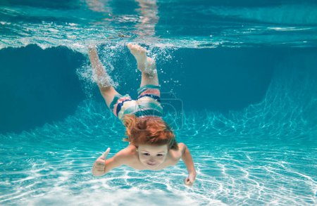 Foto de Niño feliz jugando bajo el agua en la piscina en el día de verano. Los niños juegan en el resort tropical. Vacaciones familiares en la playa. Niño nadar bajo el agua - Imagen libre de derechos