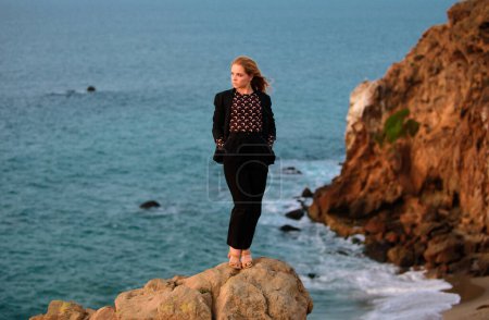 Téléchargez les photos : Femme en robe de mode d'automne sur la côte de l'océan, sur la plage rocheuse - en image libre de droit
