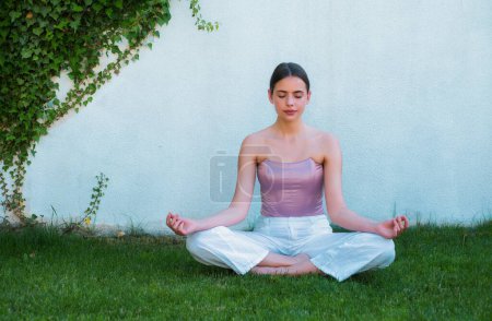 Photo for Meditation yoga woman in spring park. Woman stretching. Young girl practicing yoga, doing fit exercise, working out on green grass - Royalty Free Image