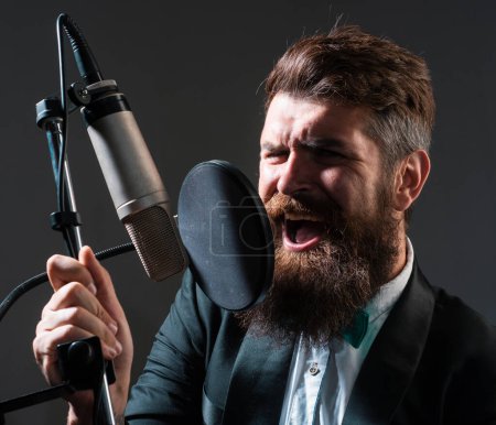 Photo for Classic singer is performing a song with a microphone while recording in a music studio - Royalty Free Image