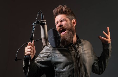Téléchargez les photos : Un chanteur dans un studio d'enregistrement. Homme barbu expressif avec microphone. Chanteuse expressive avec microphone - en image libre de droit