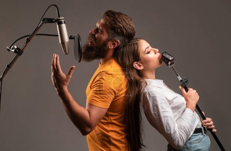 Foto de Guy y lady con caras emocionadas disfrutan de la música. Pareja cantante de karaoke. Hombre y mujer cantando con micrófono de música - Imagen libre de derechos