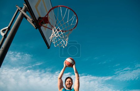 Man basketball player sportsman in shirt and shorts hold basketball ball on urban background. Sport motivation concept