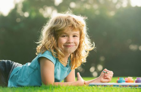 Cute little artist boy. Child boy enjoying art and craft drawing in backyard or spring park. Children drawing draw with pencils outdoor