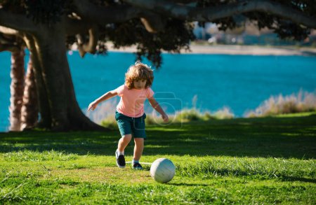 Photo for Boy child kicking football on the sports field during soccer match - Royalty Free Image