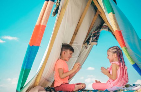Téléchargez les photos : Les enfants s'amusent dehors. Frères et sœurs jouent ensemble. Des enfants heureux jouant dans une tente. Camping enfants - en image libre de droit