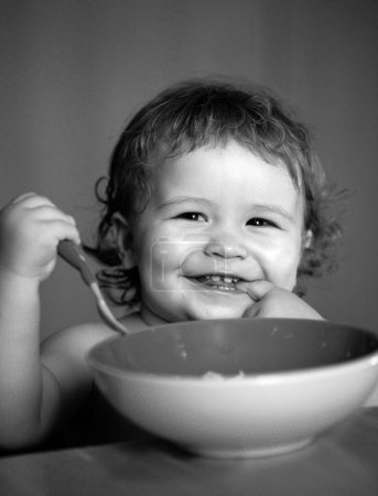 Foto de Bebé sonriente comiendo comida. Lanzamiento niño comer - Imagen libre de derechos