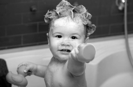Téléchargez les photos : Bébé heureux prenant un bain jouant avec des bulles de mousse. Petit enfant dans une baignoire. Enfant souriant dans la salle de bain avec canard jouet. Lavage et bain des nourrissons. Soins et hygiène des enfants - en image libre de droit