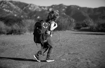 Little boy kid with backpack hiking in scenic mountains. Child local tourist goes on a local hike