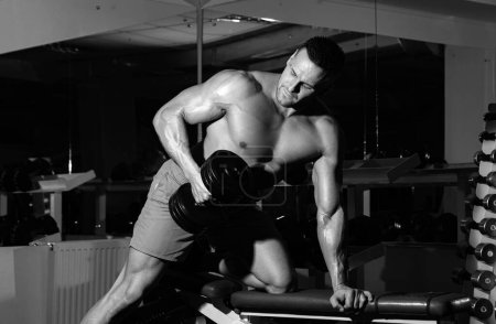Téléchargez les photos : Sport homme homme faisant biceps levage dans une salle de gym. Homme musculaire travaillant dans la salle de gym faire des exercices, mâle forte abdos torse nu - en image libre de droit