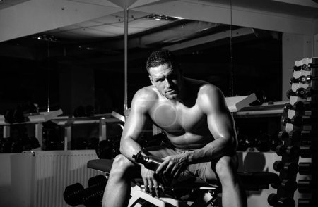 Téléchargez les photos : Portrait d'homme athlétique avec bouteille de protéines. Homme musculaire travaillant dans la salle de gym faire des exercices, mâle forte abdos torse nu - en image libre de droit
