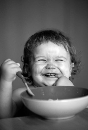 Téléchargez les photos : Bébé souriant mangeant des aliments. Lancement enfant avec cuillère - en image libre de droit
