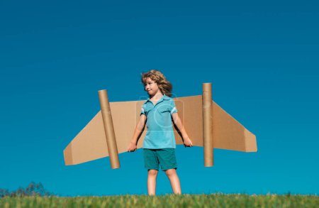 Photo for Kid imagination, child pilot with paper wings having fun at outdoor. Summer vacation and travel concept - Royalty Free Image
