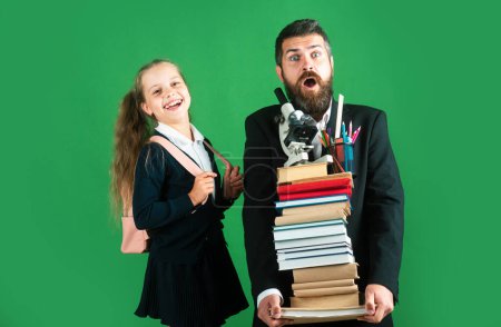 Photo for Father leading his pupil daughter to school. Portrait of modern family dad and little girls isolated on green background - Royalty Free Image
