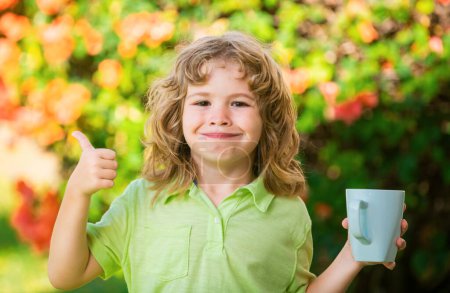 Photo for Cute kids portrait with mug, child holding a large cup with herbal tea. Happy childhood - Royalty Free Image