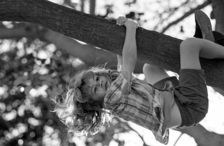 Kind auf einem Ast. Kinderklettern im Erlebnispark. Versicherungskinder. Kleine Junge Kind vor Herausforderung beim Versuch, auf einen Baum zu klettern. Kinder lieben die Natur auf dem Land