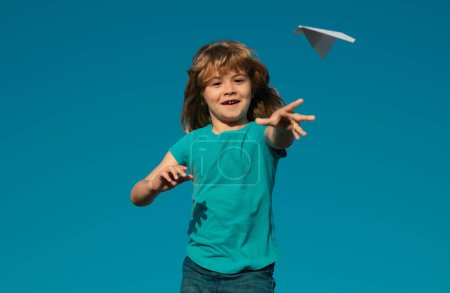 Foto de Niño sosteniendo un avión de papel al aire libre. Niño feliz jugando con el avión de papel contra el cielo. Un chico con avión de papel - Imagen libre de derechos