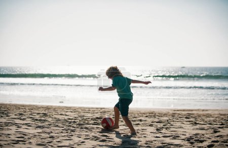 Photo for Cute little boy playing football with foot ball on sandy beach. Summer kid sport - Royalty Free Image