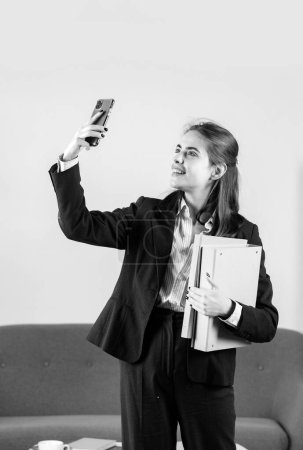 Foto de Feliz joven mujer de negocios sonriente freelancer o empleado ceo haciendo llamada telefónica en la oficina. Chica contable bonita en el escritorio en el interior de la oficina - Imagen libre de derechos