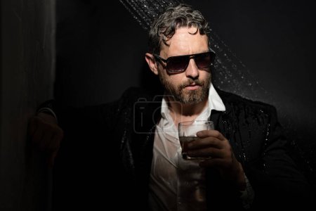 Photo for Drunk business man. Disheveled man in suit in bathroom after night party. Man drinking a whiskey after party in night club. Alcohol and drugs concept. Stressed business man under shower - Royalty Free Image