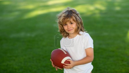 Téléchargez les photos : Football américain. Un garçon américain jouant au football américain ou au rugby dans un parc. Des gamins sportifs. Joueur de football tenant le ballon - en image libre de droit