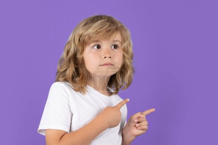 Photo for Child boy looking away, pointing finger on isolated studio background. Kid pointing to copyspace, showing promo offers, points away. Advertisement promo product concept - Royalty Free Image