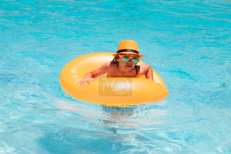 Foto de Niño 7, 8, 9 años de edad nadar en anillo flotante en la piscina. Niños verano divertido cara - Imagen libre de derechos