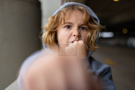 Photo for Aggressive child. Aggression kid boy fighting on street. Angry aggression kid with fist. Aggression fight kid. Bullied, physical abuse, children fighting. Aggression little boy. Kids bad behavioral - Royalty Free Image