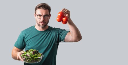 Téléchargez les photos : Une nourriture saine. Homme tenir salade de tomates et légumes frais isolé sur fond gris, portrait studio. Grande bannière de légumes - en image libre de droit