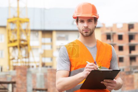 Téléchargez les photos : Ouvrier de la construction masculin en vêtements de travail et un casque de construction. Concept de construction et de chantier - en image libre de droit