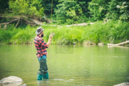 Téléchargez les photos : Pêcheur pêchant sur un rever. Pêcheur détendu homme avec une canne à pêche un jour d'été. Homme tirant canne à pêche - en image libre de droit