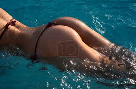 Téléchargez les photos : Sexy curves girl butt in bikini in pool. Sexy buttocks. Young woman shows a beautiful ass buttocks in water. Summer background - en image libre de droit