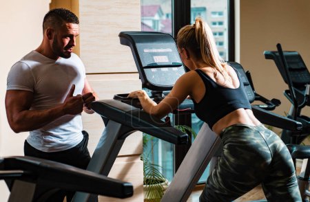 Photo for Sporty couple workout cardio exercise gym. Sportive couple in gym. Personal trainer fitness instructor helping woman doing cardio workout running - Royalty Free Image